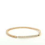 A gold-colored bracelet with a diamond-encrusted bar on the clasp.