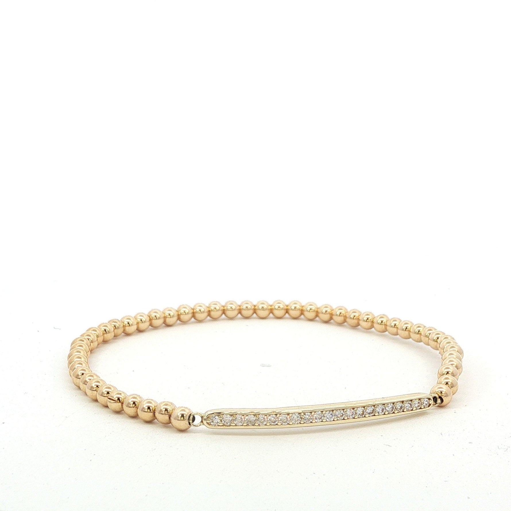 A gold-colored bracelet with a diamond-encrusted bar on the clasp.