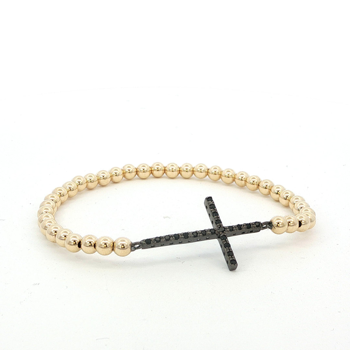 A gold-colored beaded bracelet with a black cross-shaped charm attached to it.