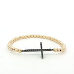 A gold-colored beaded bracelet with a black cross-shaped charm attached to it.