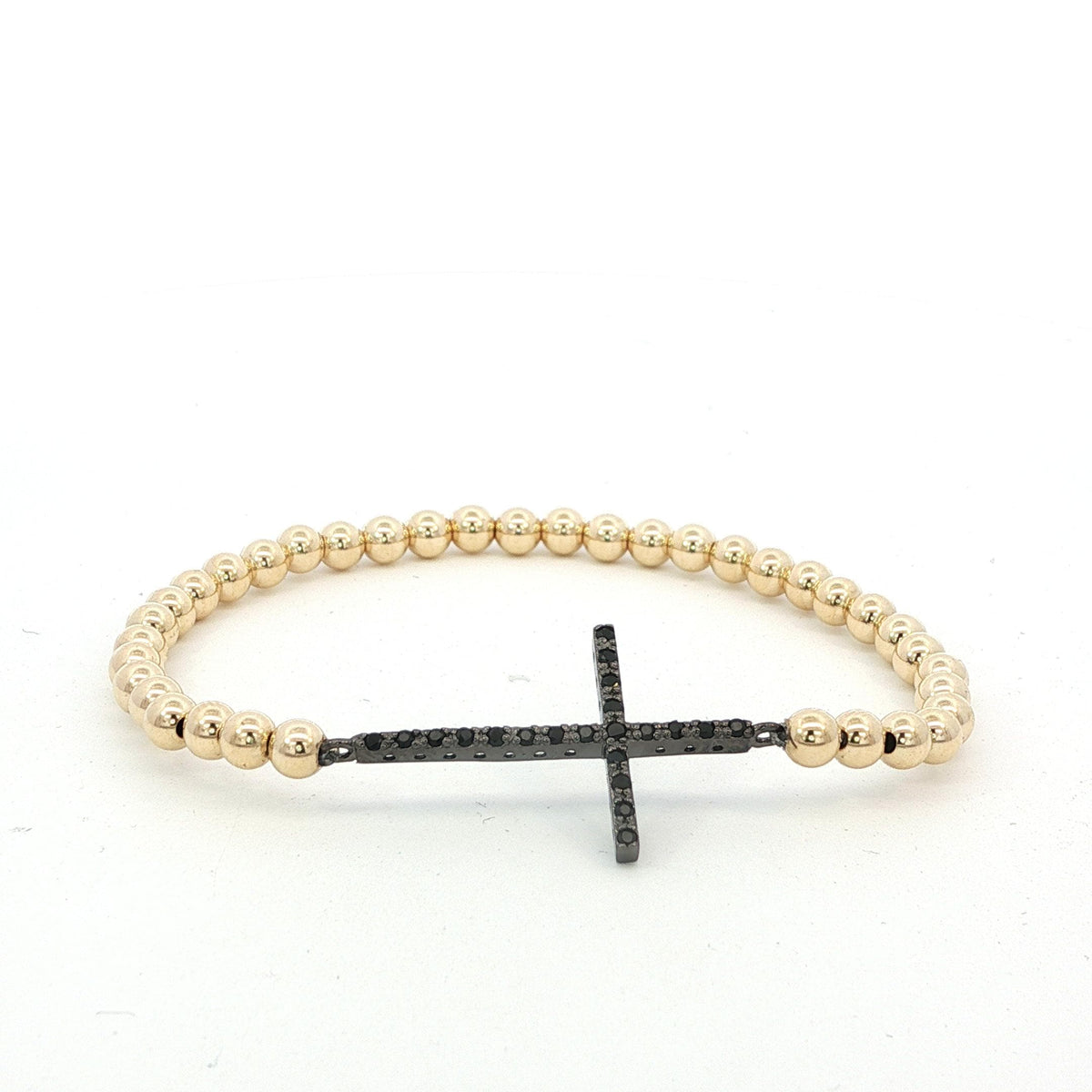 A gold-colored beaded bracelet with a black cross-shaped charm attached to it.
