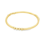 A gold-colored bracelet with a curved design and small round beads on the ends.