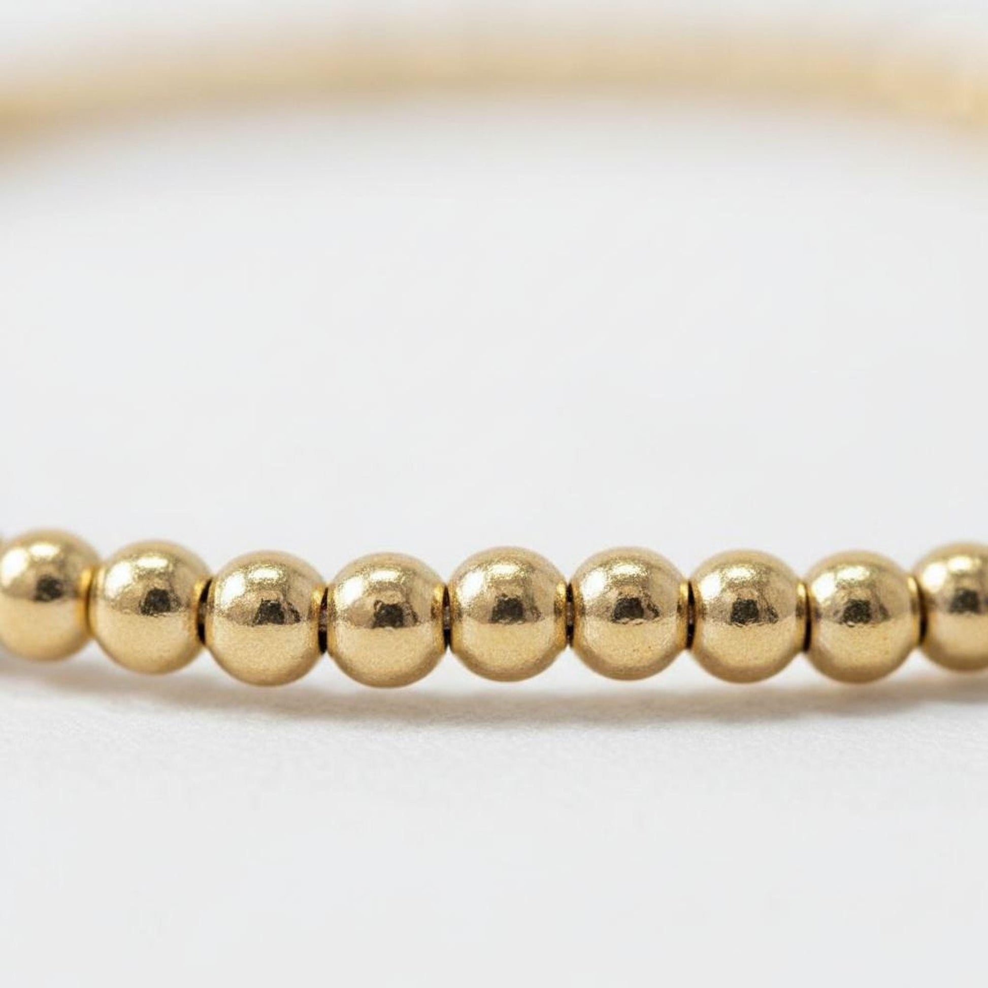A row of shiny gold beads on a white background.