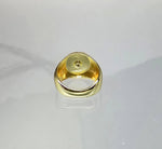 A gold ring with a small hole in the center, placed on a reflective surface.
